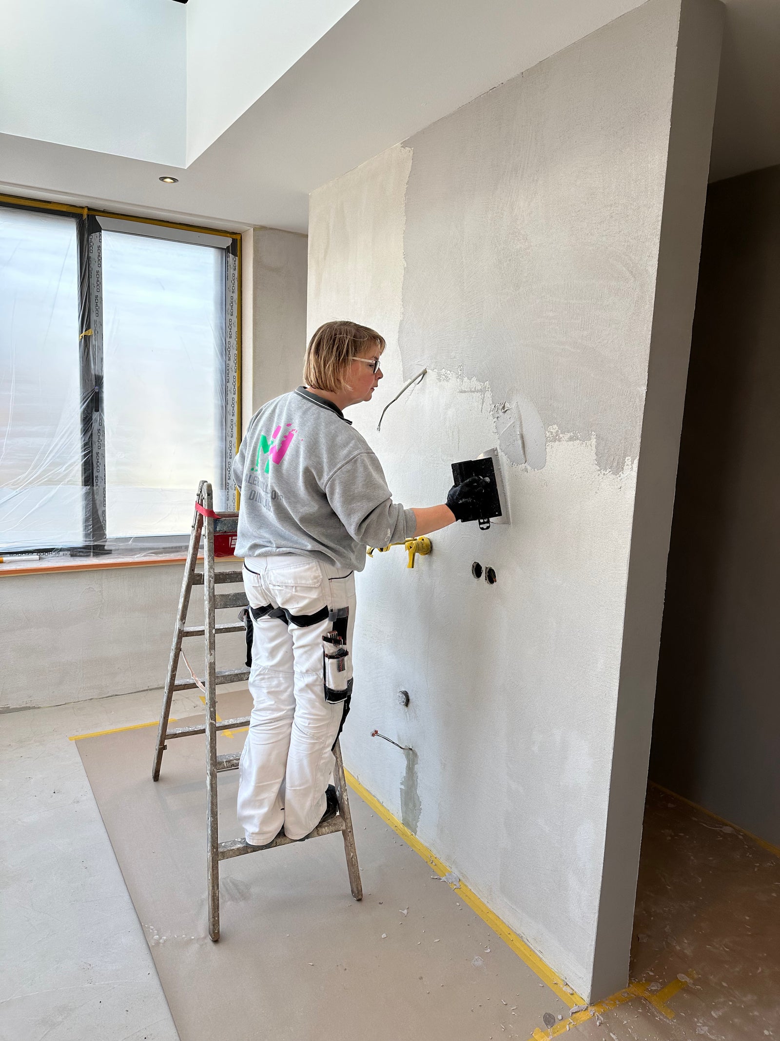Maler streicht eine Wand in einem hellen Raum